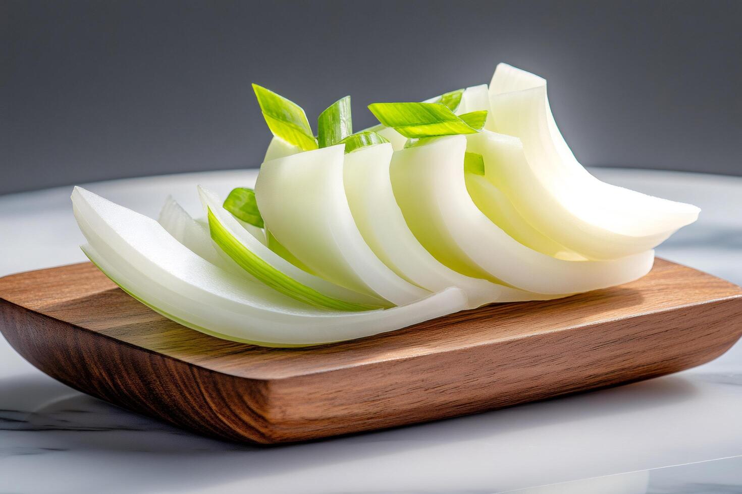 Sliced white onion with chopped chives on wooden cutting board photo