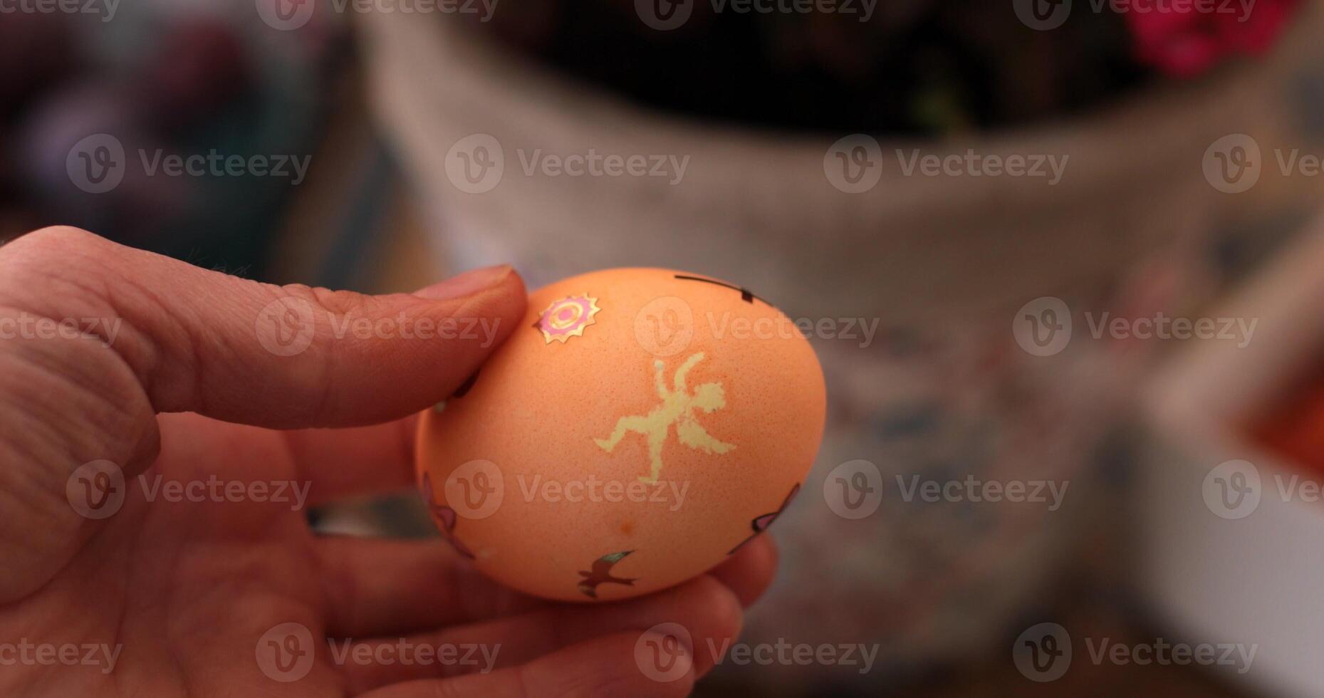 Hand holding decorated Easter egg featuring colorful images while preparing for a joyful Easter celebration with family and friends through fun coloring egg activities photo