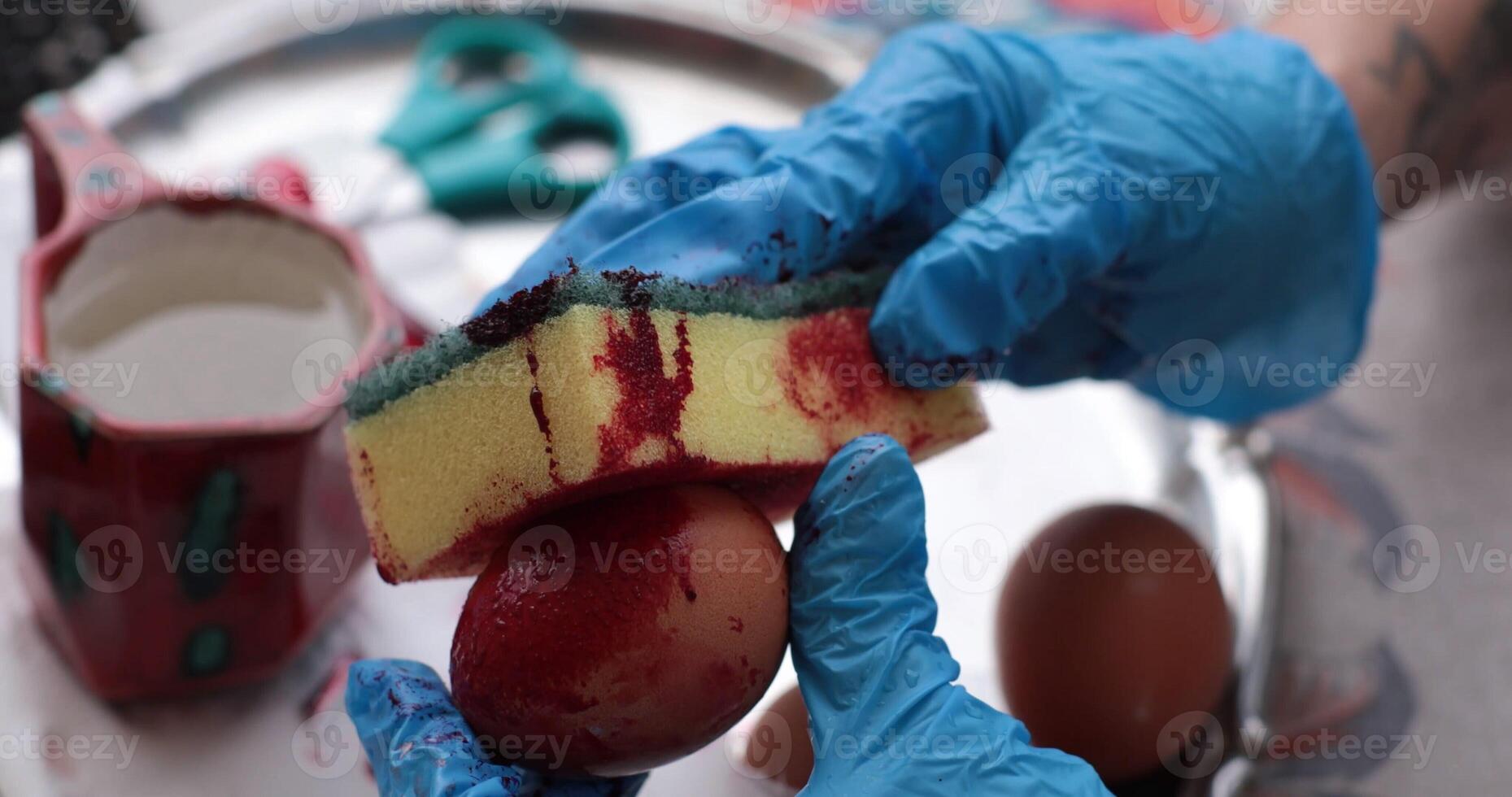 Creative process of coloring Easter eggs with red dye using a sponge technique in a cozy indoor setting during the festive spring season photo
