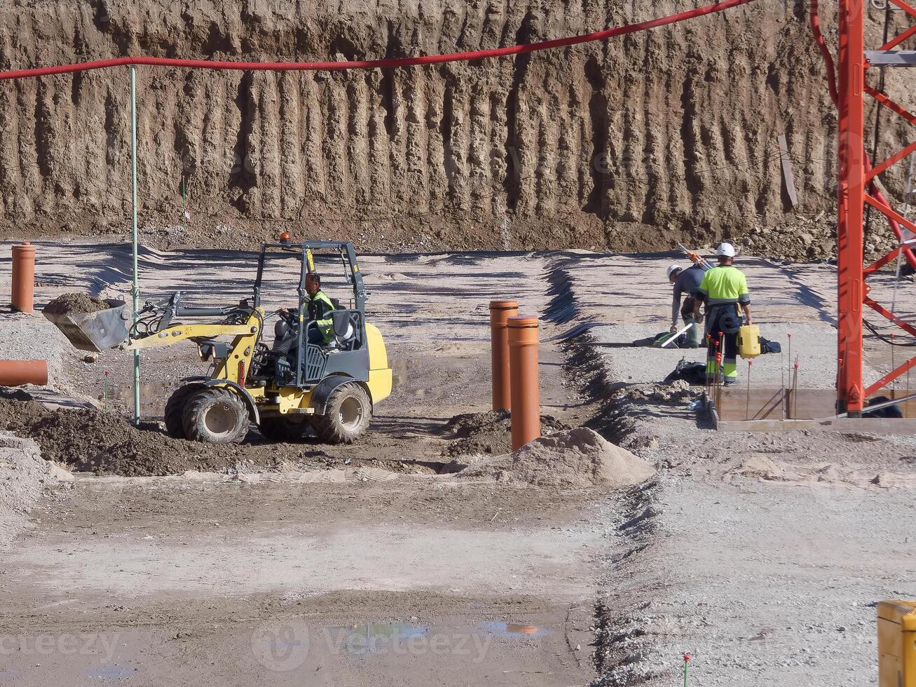 Construction site activity featuring machinery and workers at a development project in sunny conditions photo