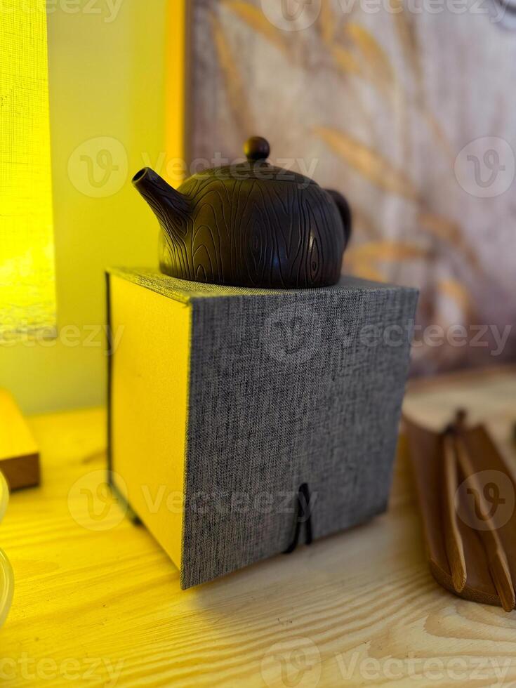 Dark clay teapot resting on textile box under warm light. Calm ritual, mindful aesthetics and cultural appreciation in tea ceremony photo