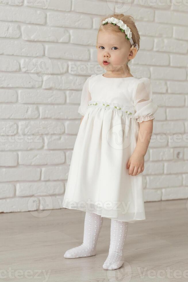 Baby child with hearing aids and cochlear implants on white brick wall. Deaf and health and diversity concept photo