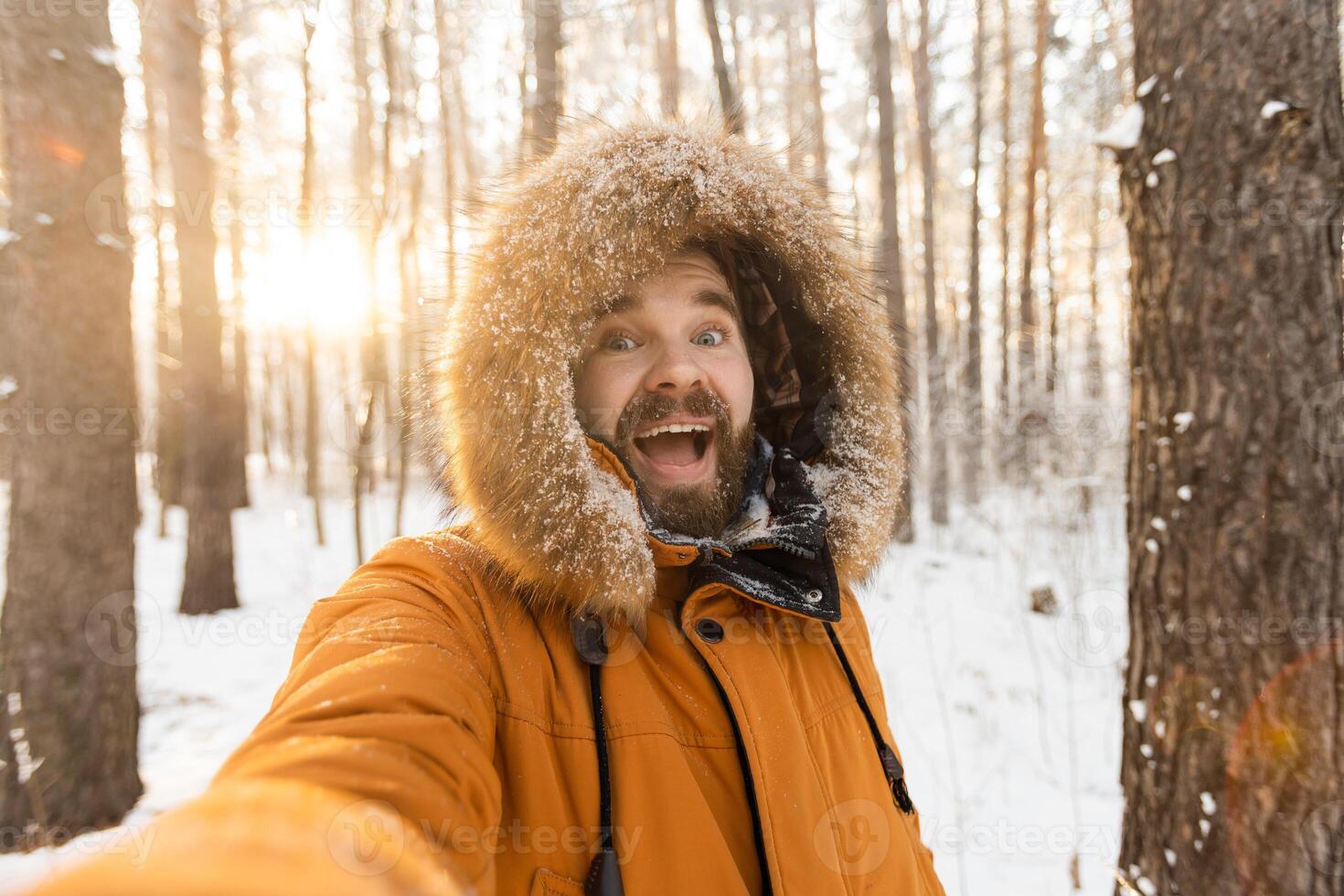 Excited man enjoying winter forest walk and taking selfie. Joy, freedom and connection with nature during the snowy season. photo