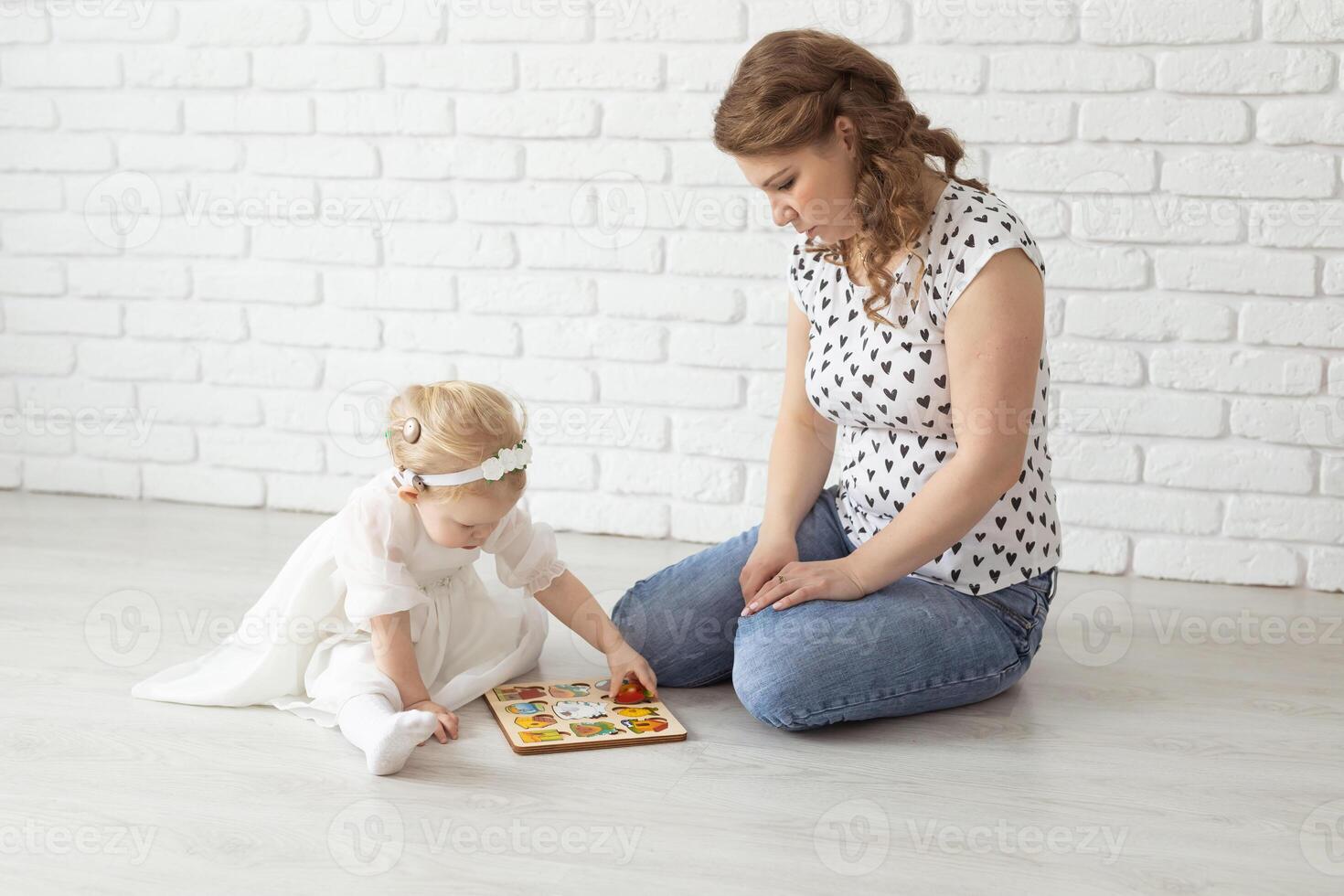 Baby child with hearing aids and cochlear implants plays on floor. Deaf and rehabilitation concept photo