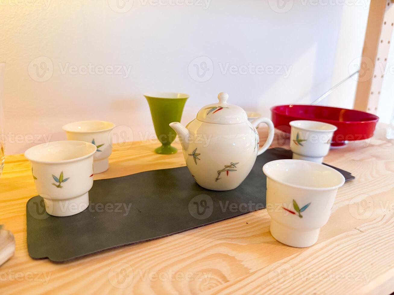 Porcelain teapot and cups arranged on wooden table. Mindfulness, ritual and harmony in the context of traditional tea ceremony photo