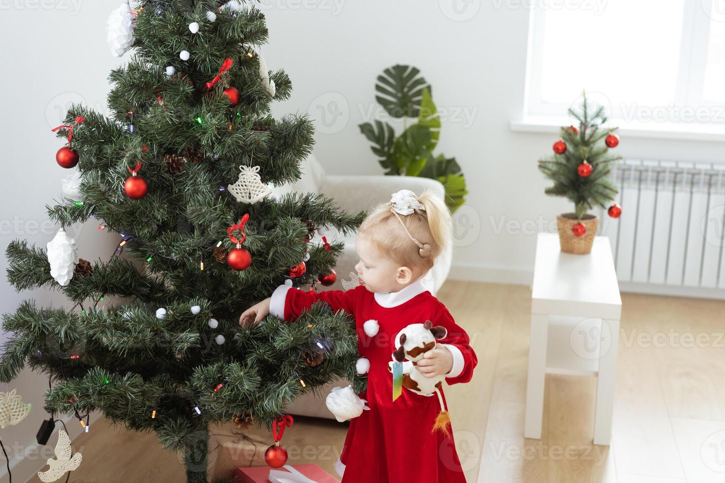 Toddler child with cochlear implant decorating christmas tree - deafness and innovating medical technologies for hearing aid photo
