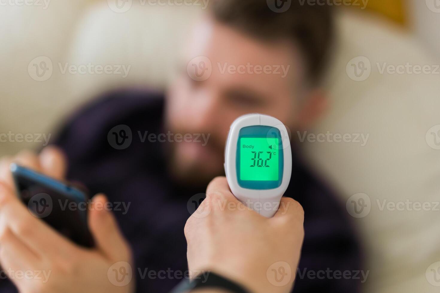 Close up of infrared digital forehead thermometer in hand,fever examination and measures to prevent and screen people check body temperature during its reopening after COVID-19 Coronavirus Lockdown photo