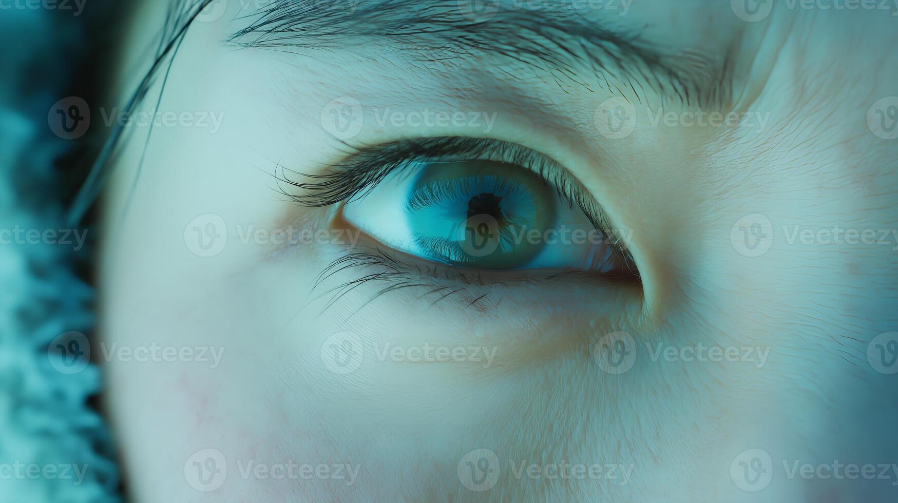 Womans eye is open and has a greenish tint. The eye is surrounded by a blue background photo