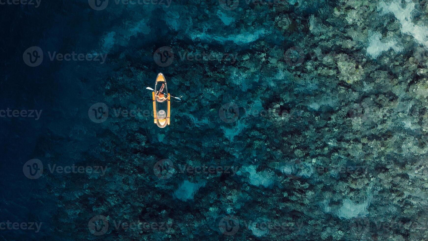 Kayaking in blue sea on transparent kayak. Drone view with copy space photo