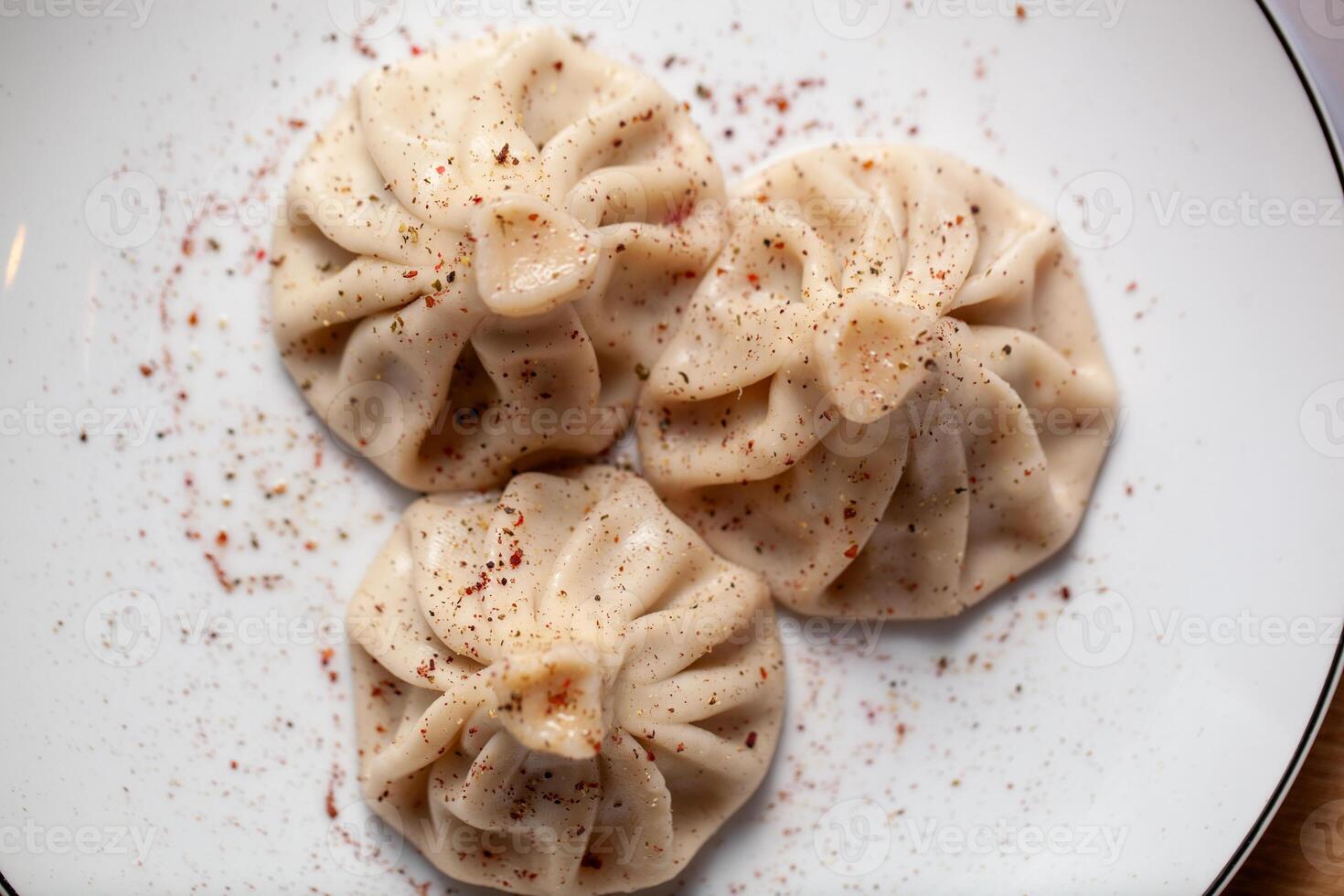 Top view of three traditional khinkali dumplings garnished with spices on a plate photo