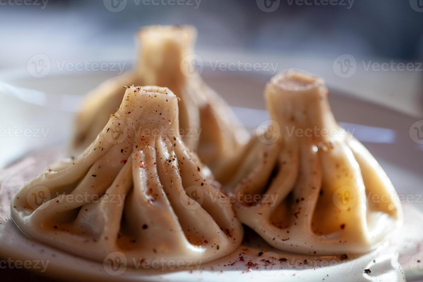 Traditional khinkali dumplings sprinkled with spices on a white plate and softly lit photo