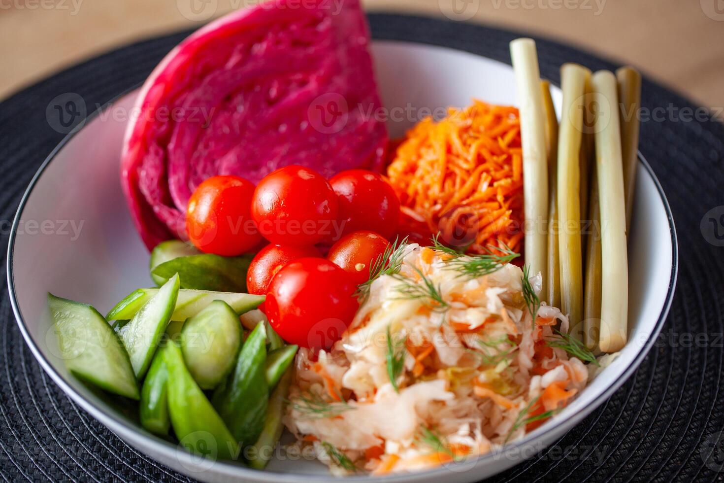 A selection of traditional Russian pickled vegetables including cabbage cherry tomatoes and cucumbers served in a white bowl photo