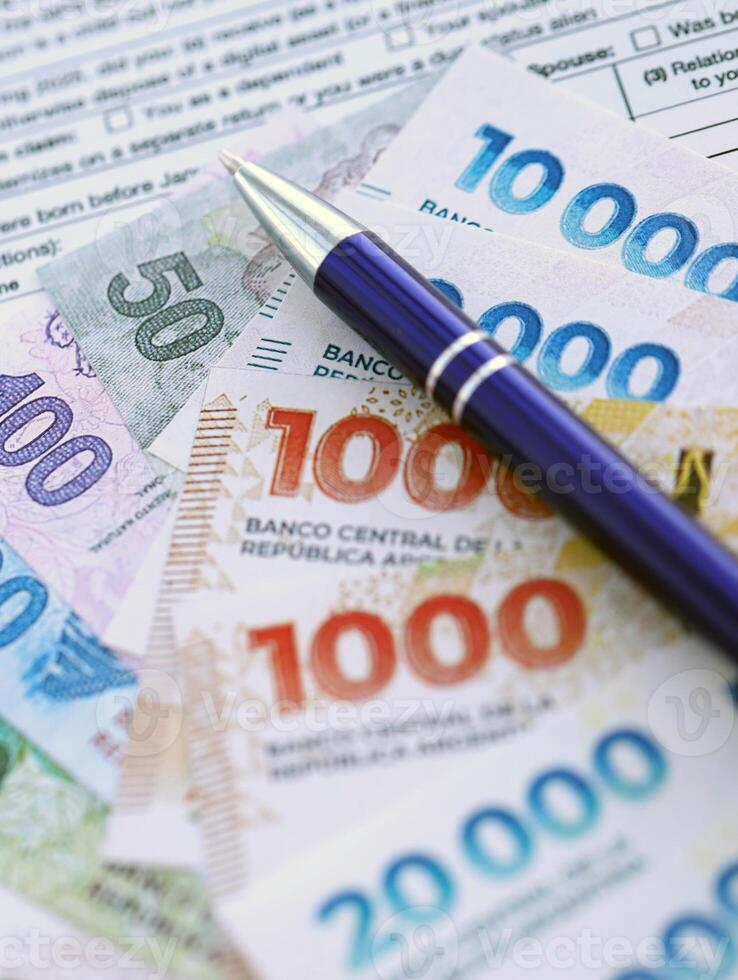 Argentine pesos bills in big amount lies on table with pen and tax forms close up photo