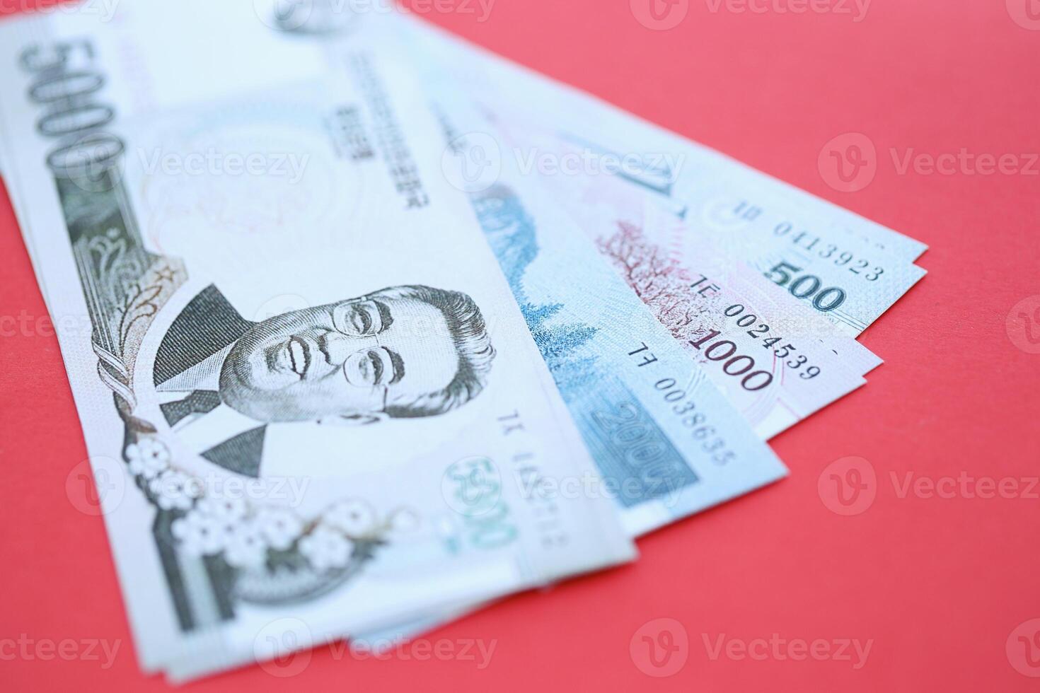 North Korean won money in big amount lies on red color table close up photo