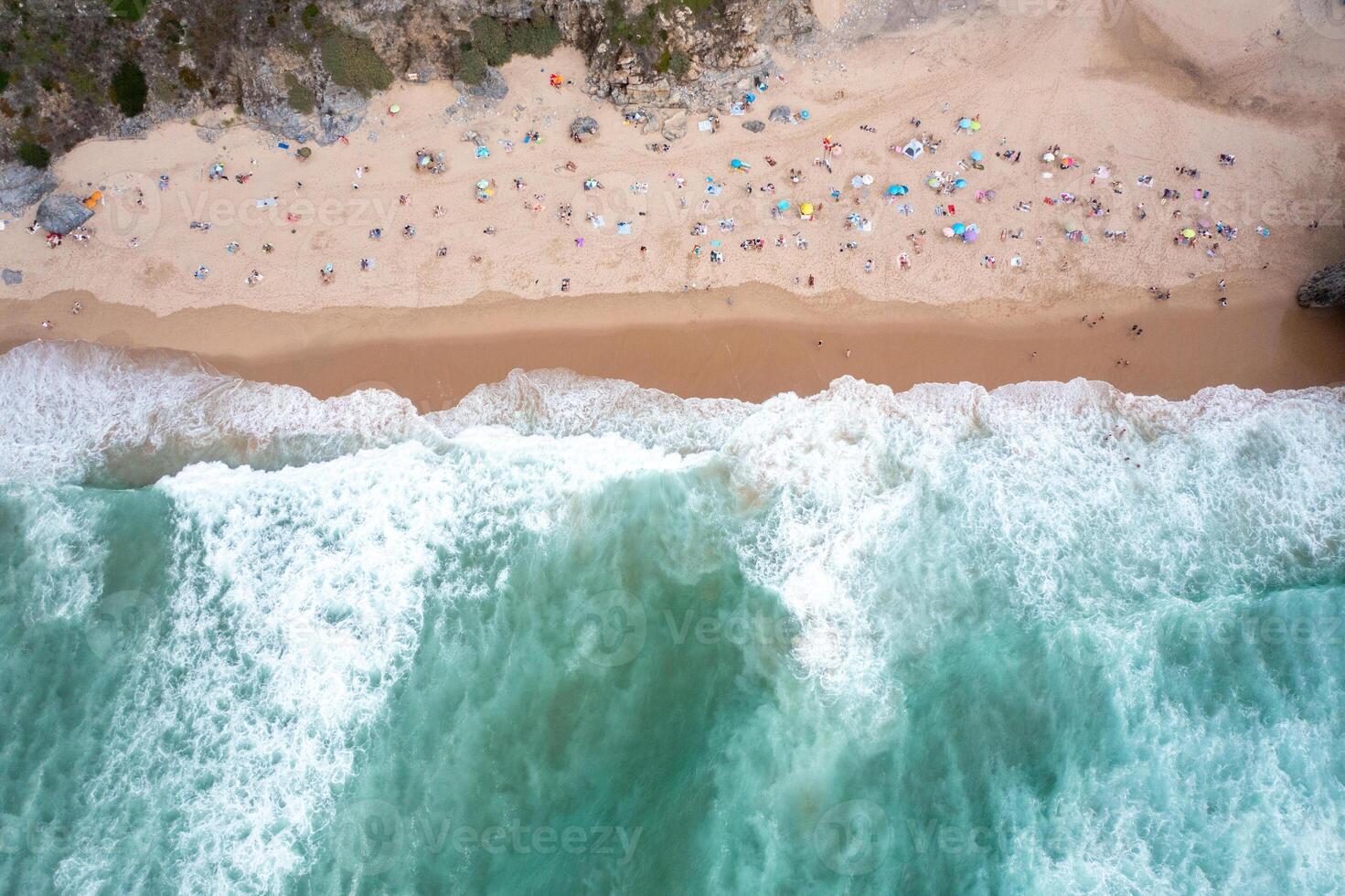 Ocean beach with turquoise waters and tourists relaxing on sandy seashore photo