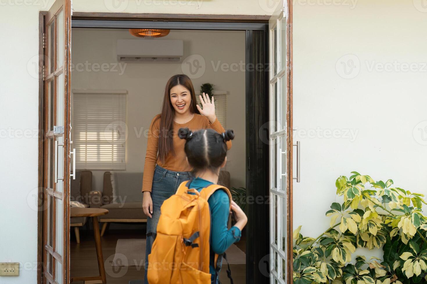 Warm Send-off and Daughter First Day of School. A young girl waves goodbye to her mother at the door. photo