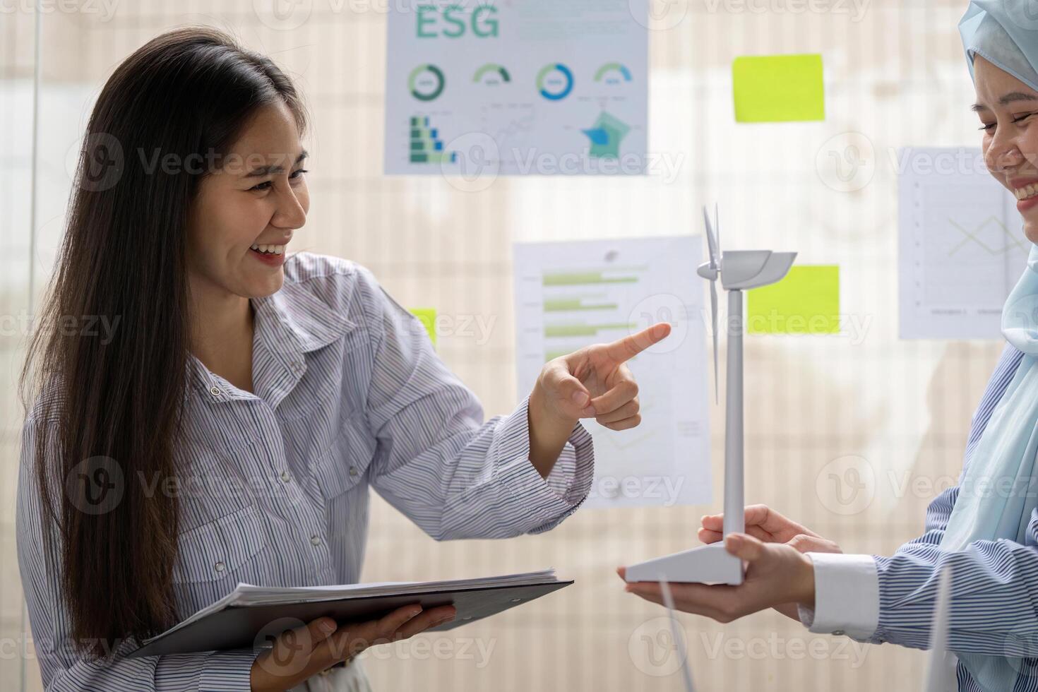 Innovative Dialogue on Sustainable Energy. A woman joyfully explains wind turbine models while discussing their potential impact on ESG. photo