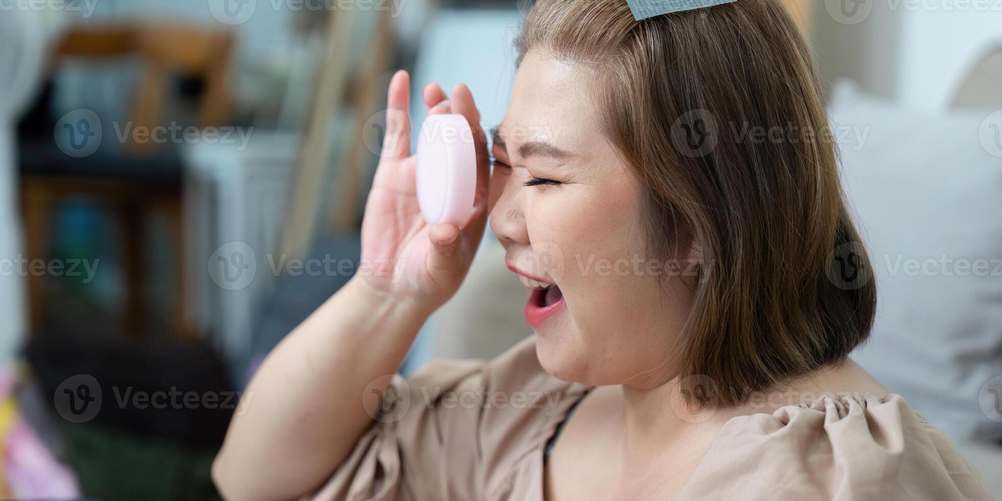 Makeup Application and Joy. A woman playfully applying makeup while smiling, emphasizing a vibrant beauty routine. photo