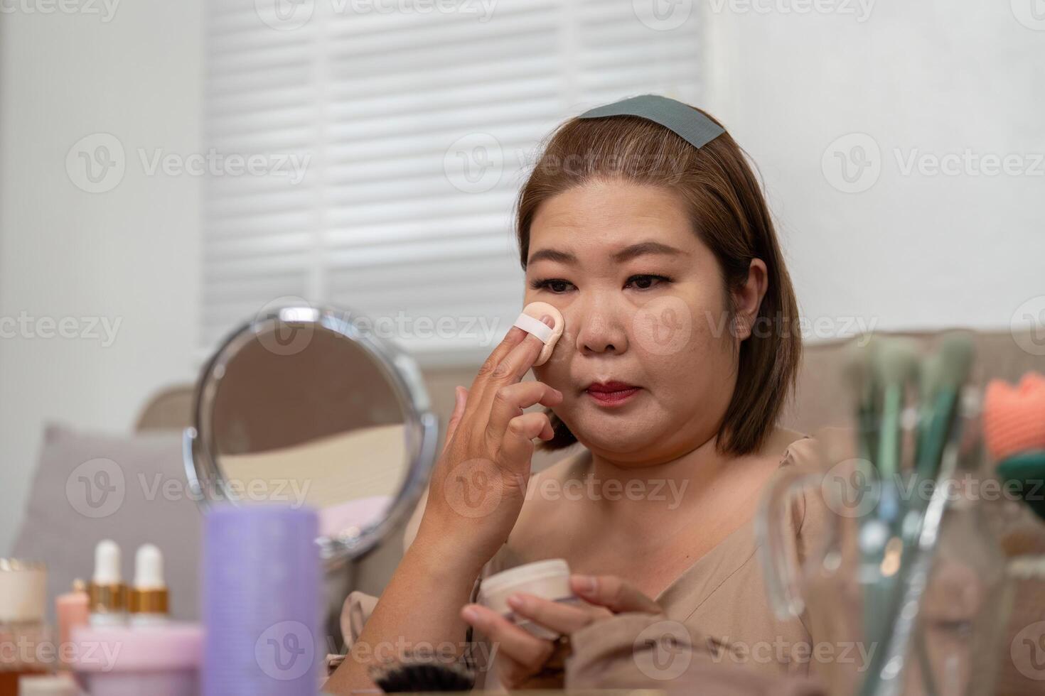Beauty Routine and Makeup Application. A woman applying foundation with a sponge, focusing on her skincare and makeup routine. photo