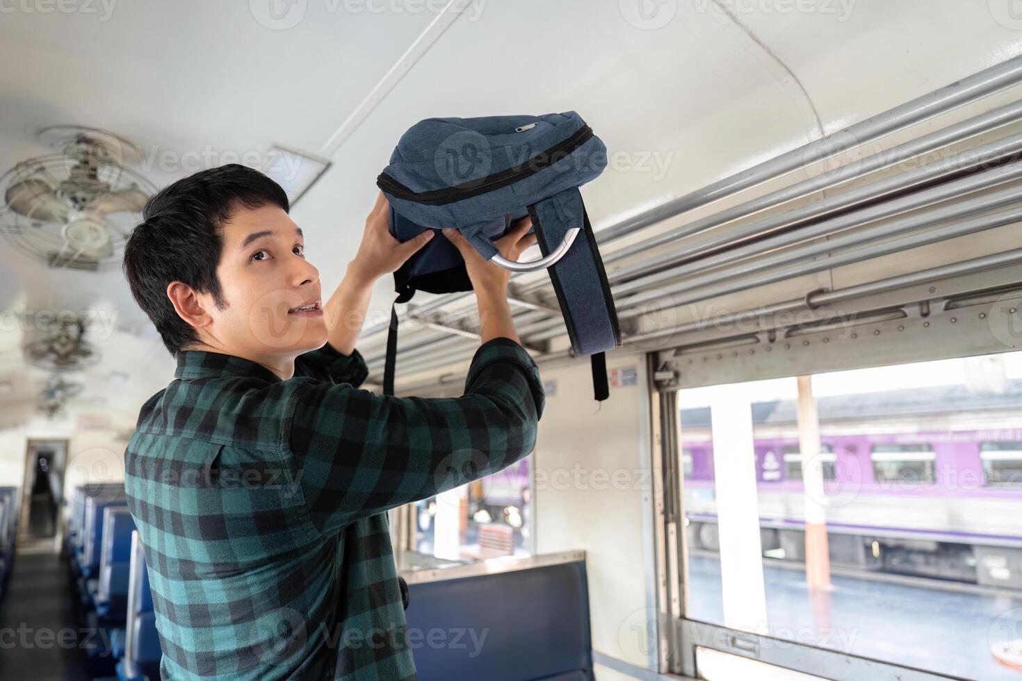 Travel and Preparation. A young man placing his backpack in the overhead compartment as he embarks on an exciting journey. photo
