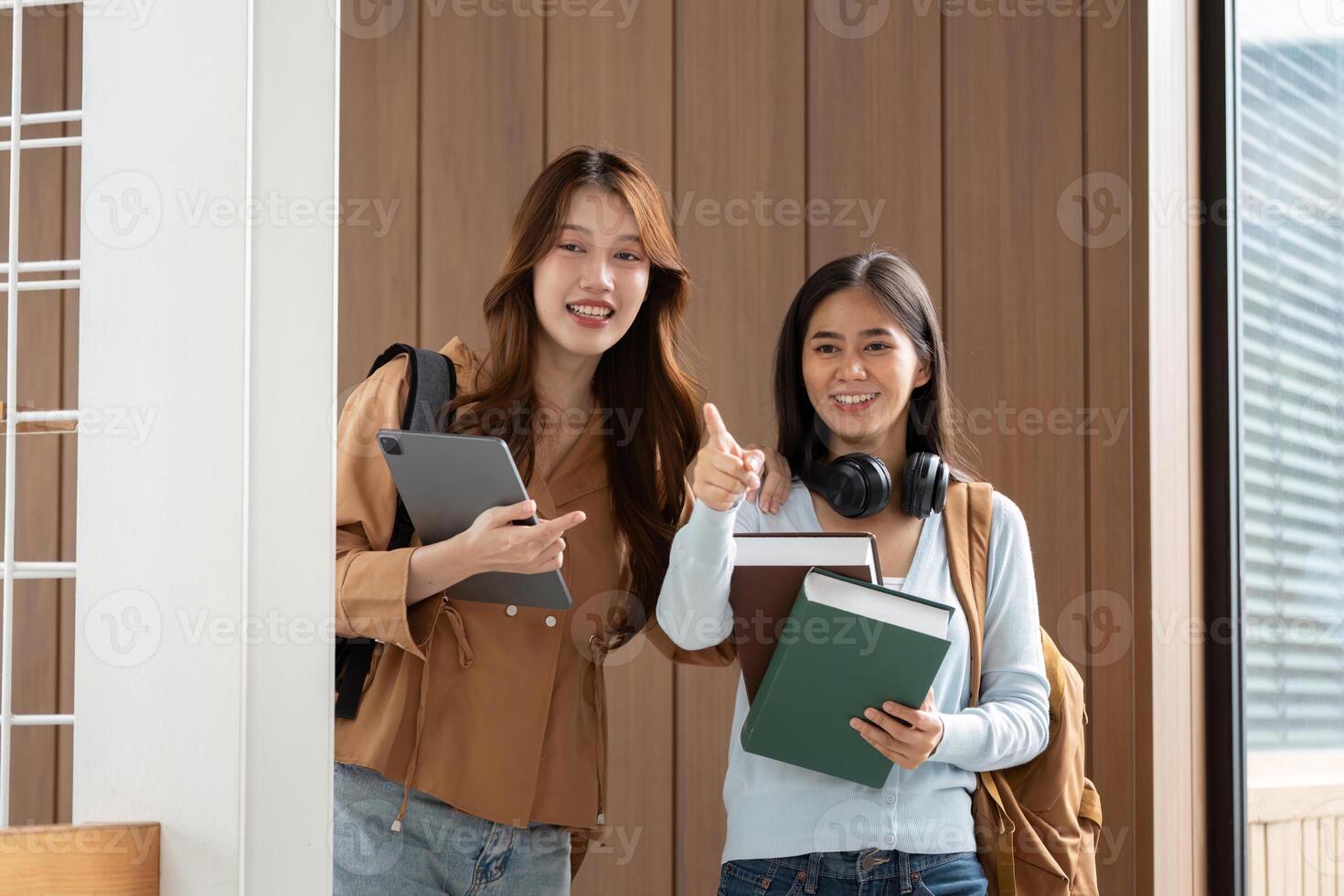 Friendship and Academic Success. Two students posing with their books and devices after a productive session. photo
