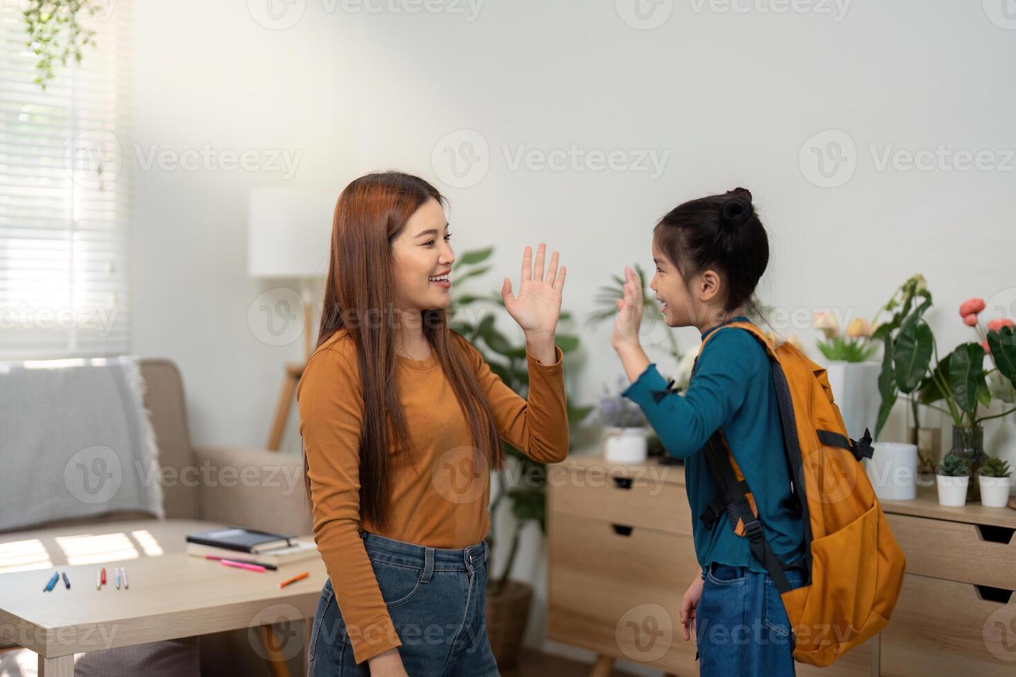 Back to School and High-Fives. A mother and daughter celebrate with a playful high-five before leaving for school. photo