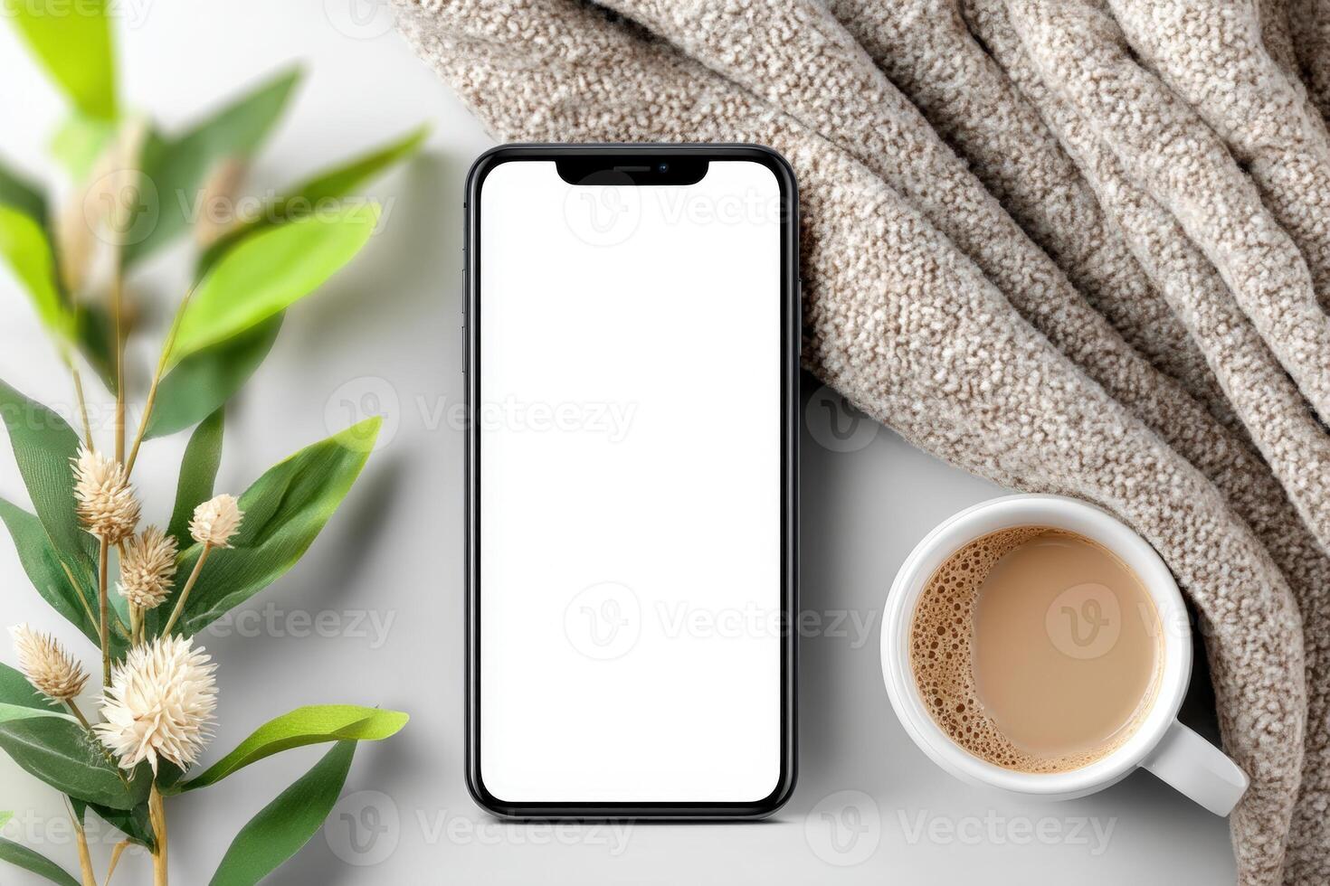 Cozy morning setup with coffee, phone, and greenery on soft blanket in bright light photo
