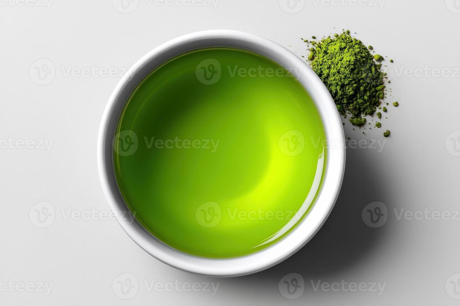 Vibrant green matcha tea in a white bowl with powdered matcha beside it on a plain surface photo