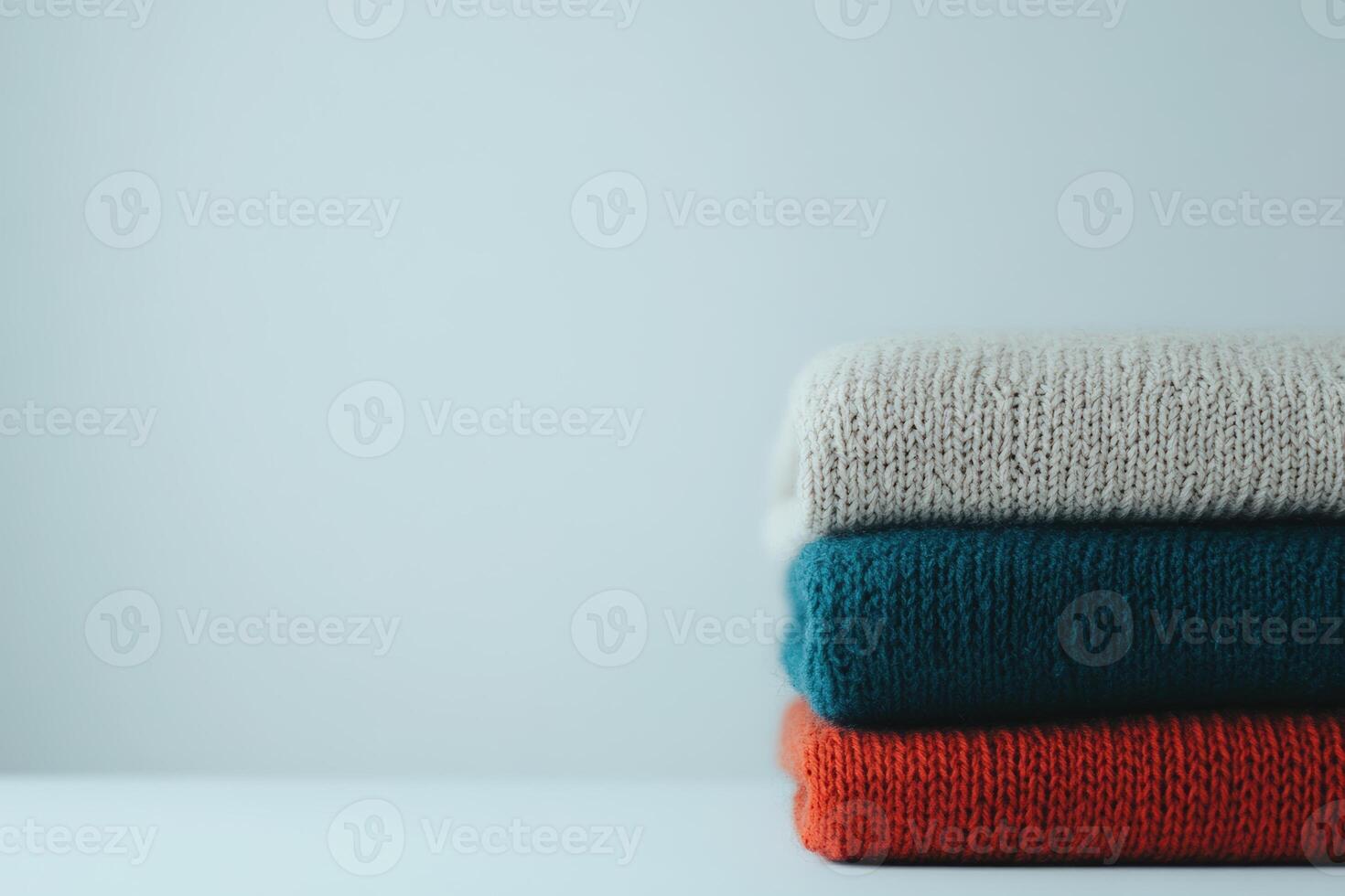 Cozy stacked sweaters in neutral and vibrant colors on a simple background photo