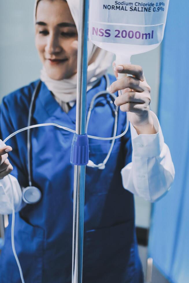 A woman in a blue uniform holding an iv stand photo