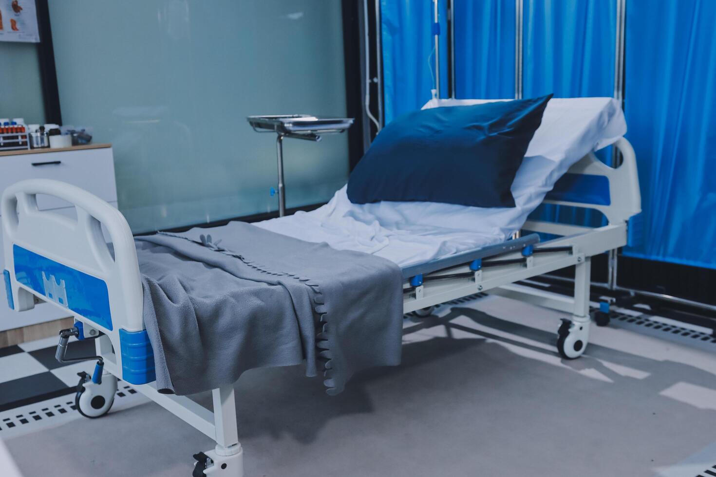 A hospital bed with blue curtains and a blue pillow photo