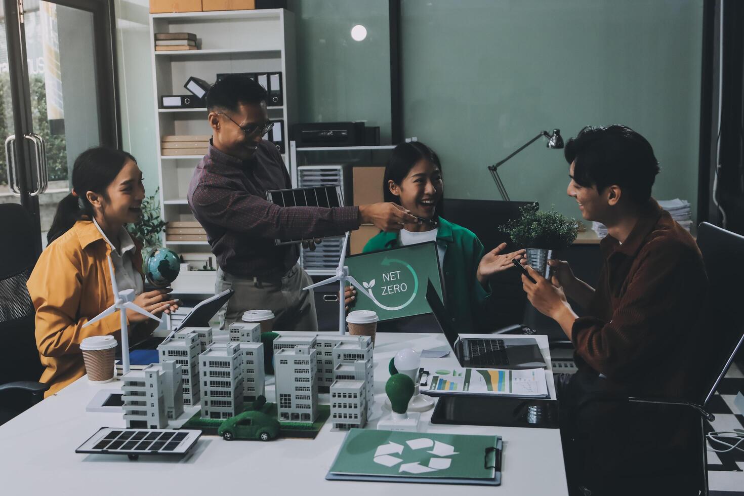 A group of people sitting around a table with a recycling sign photo