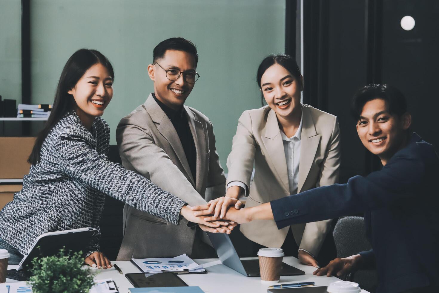 Asian business people holding hands in an office photo