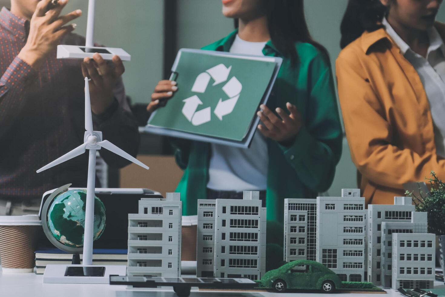 A group of people are standing around a table with a recycling sign photo