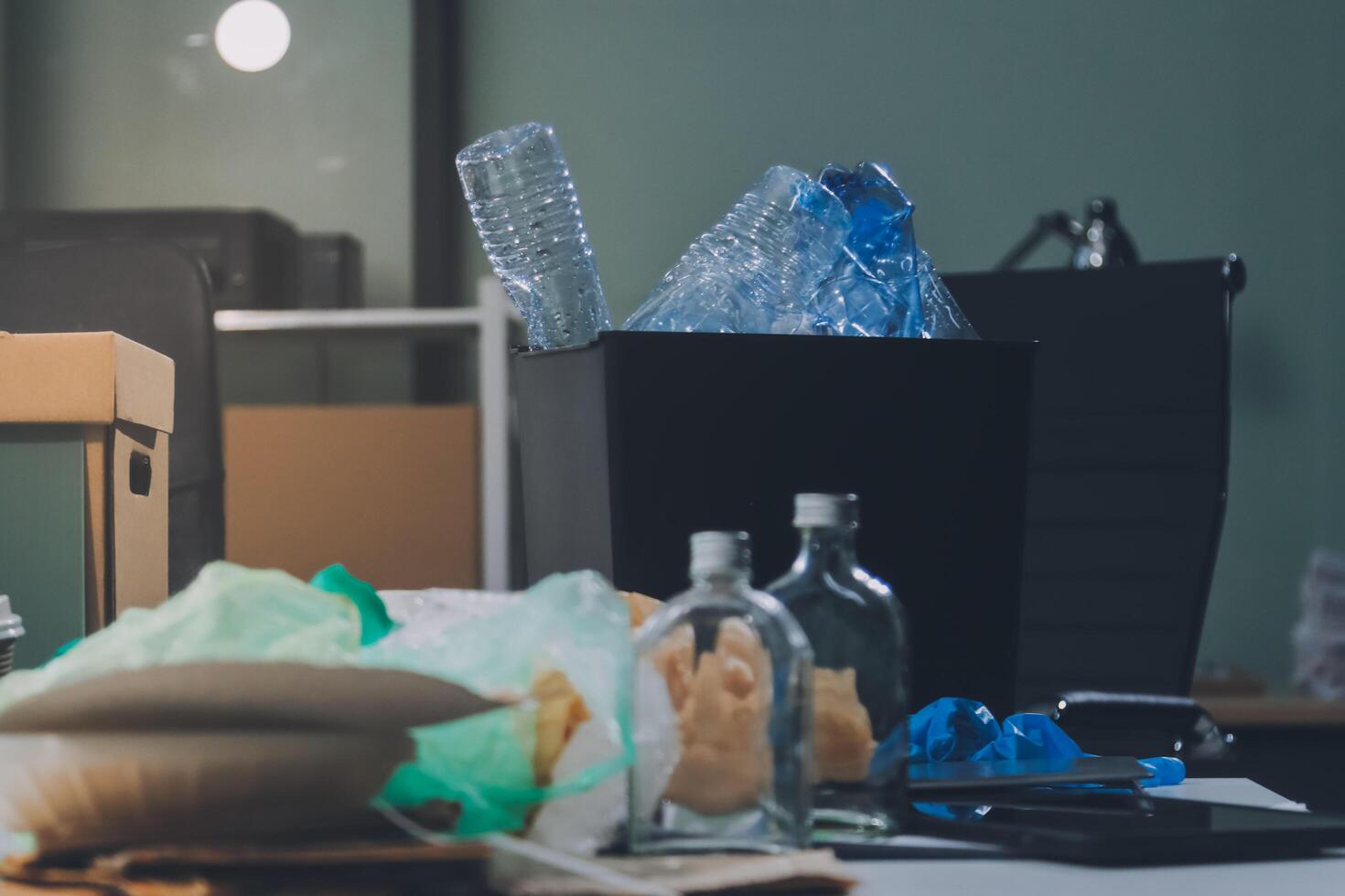 A desk with a trash can, a laptop, and other items photo