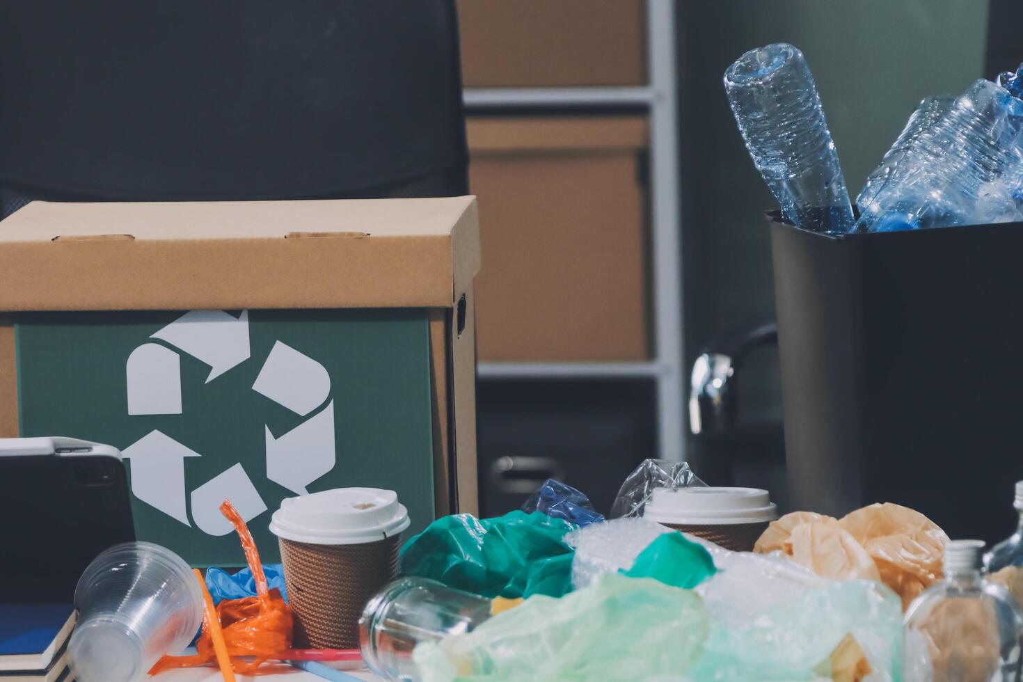 A desk with a trash can, a laptop, and a cup of coffee photo