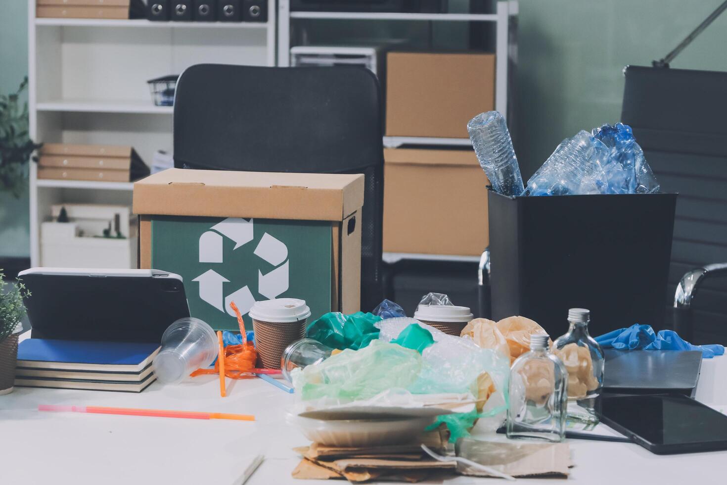 A desk with a laptop, trash can, and other items photo