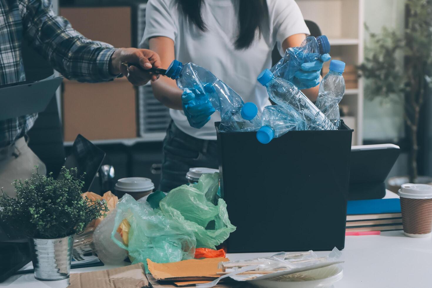 A man and woman are working on a desk with trash and plastic bottles photo