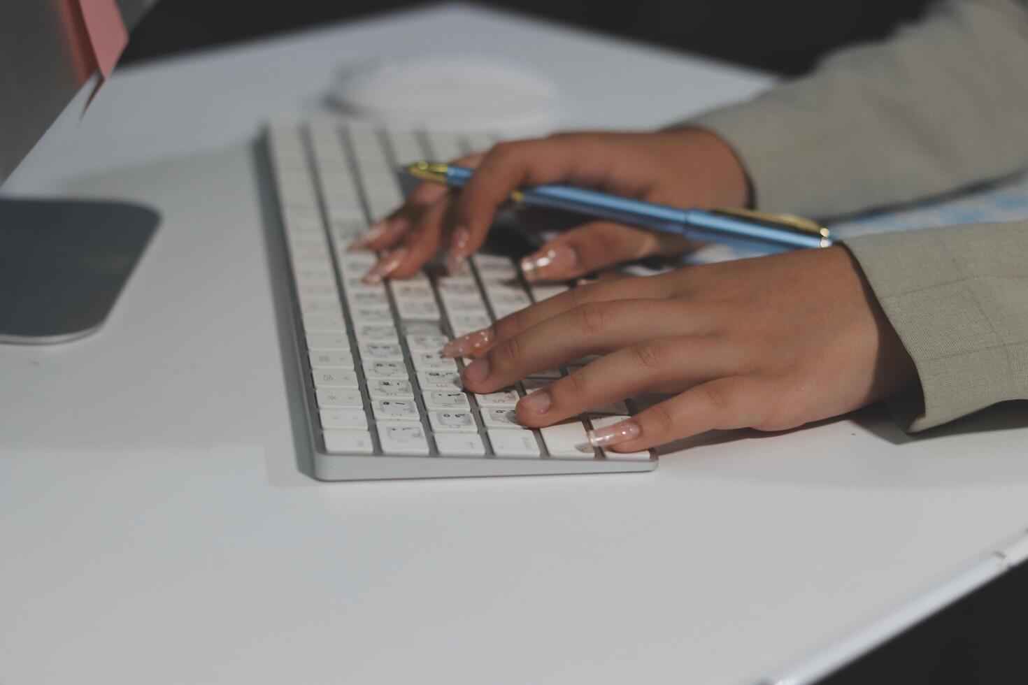 A person typing on a keyboard with a pen photo