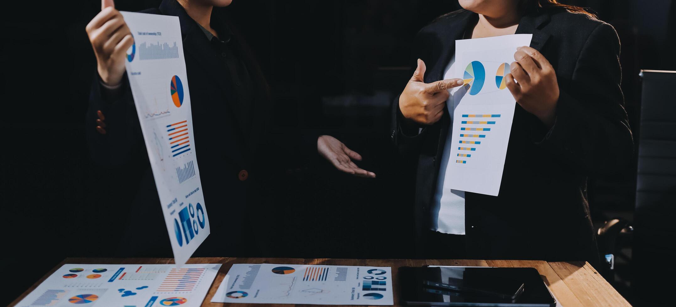 Two business people standing over a table with graphs and papers photo