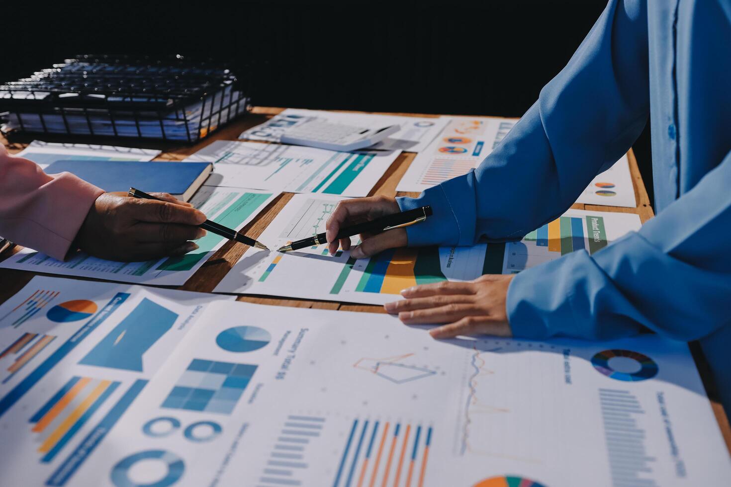 Two people working on a table with graphs and papers photo