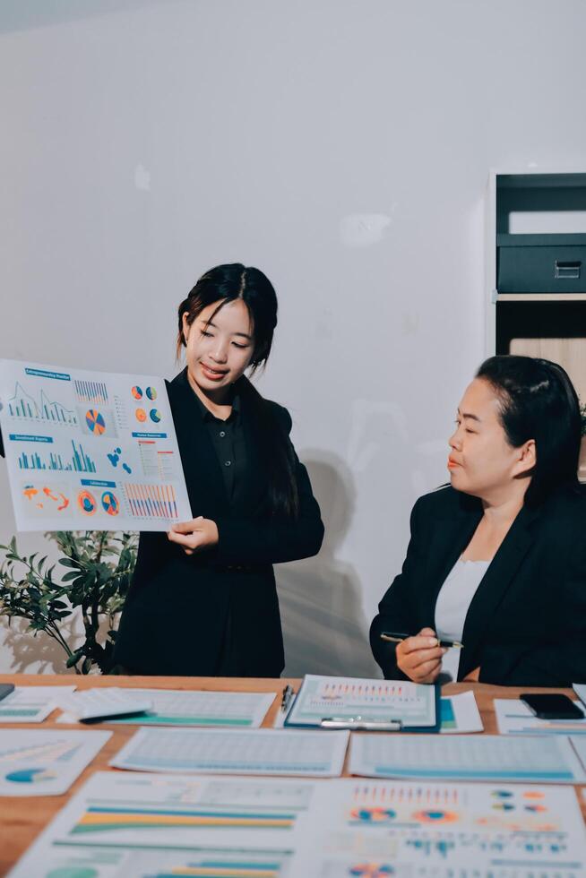 Two businesswomen in business attire looking at graphs photo