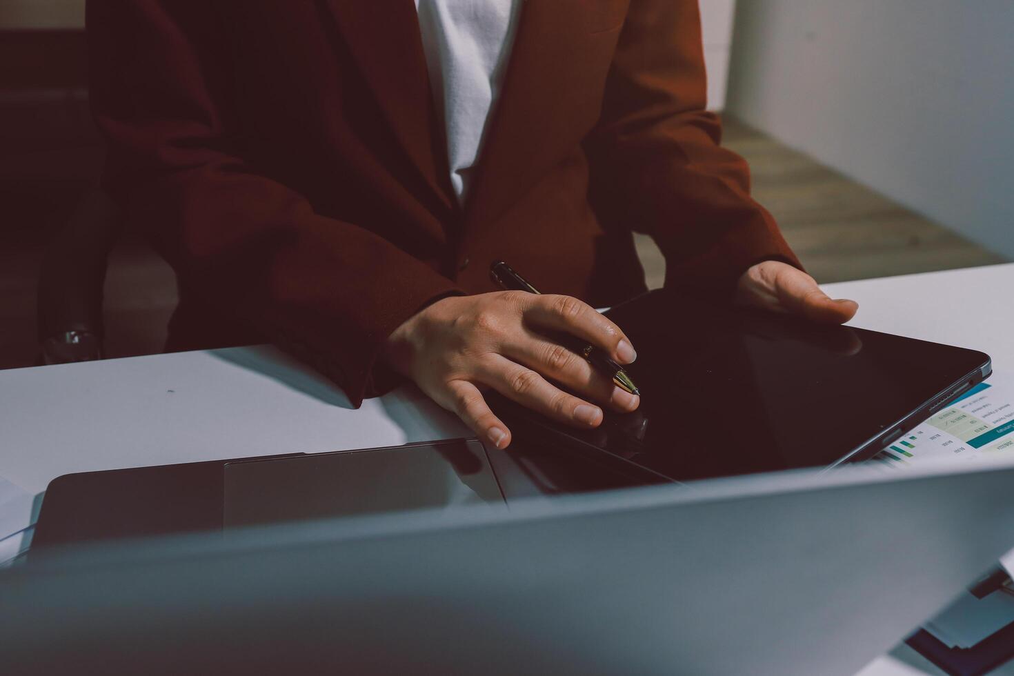 A person in a suit sitting at a desk with a tablet photo