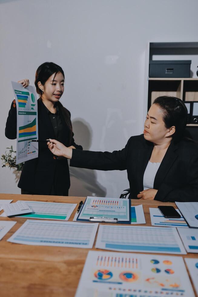 Two businesswomen in suits standing at a table with papers photo
