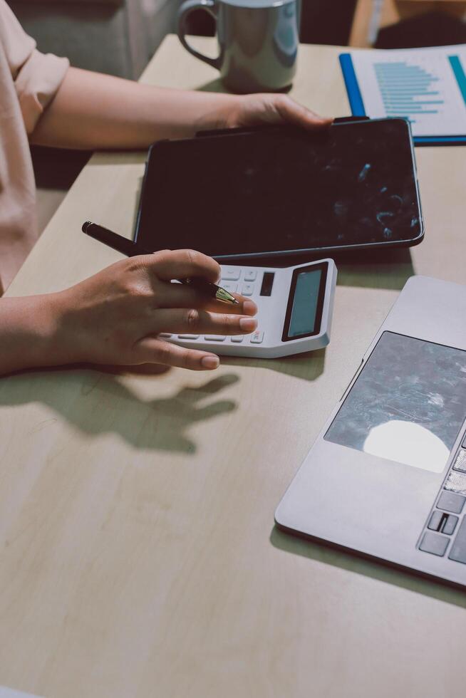 A person sitting at a table with a laptop and a calculator photo