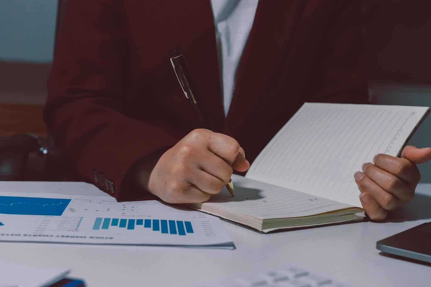 A person in a suit is writing in a notebook photo