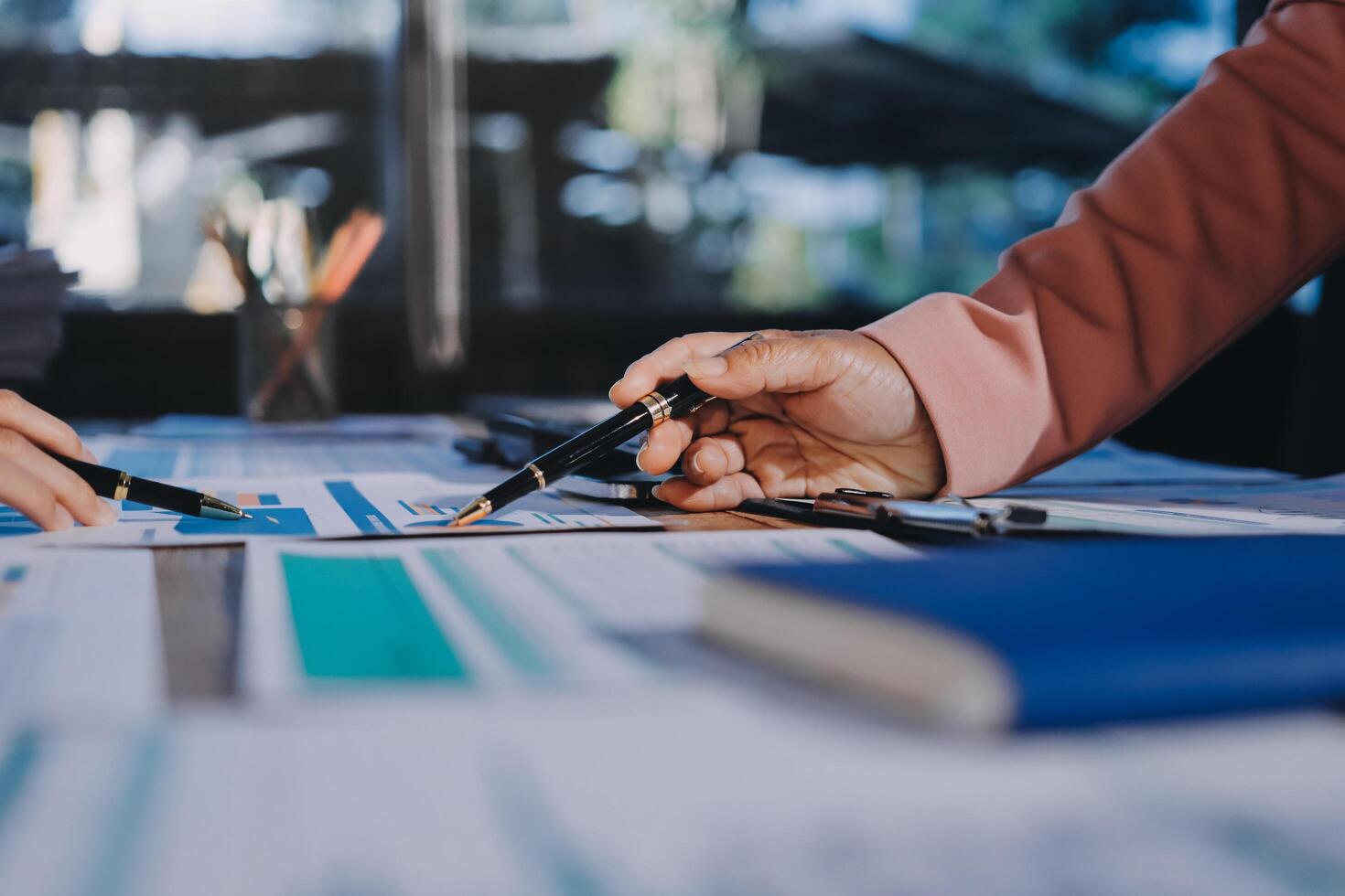 Two people working on a document with pens and papers photo