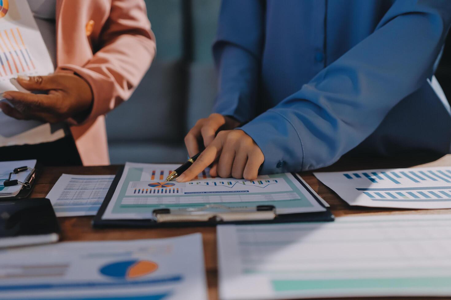 Two business people are working on a document with papers and graphs photo