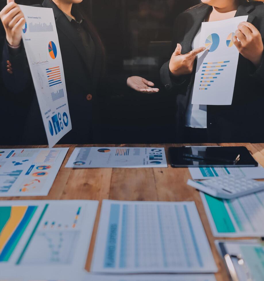 Two business people standing around a table with graphs and papers photo