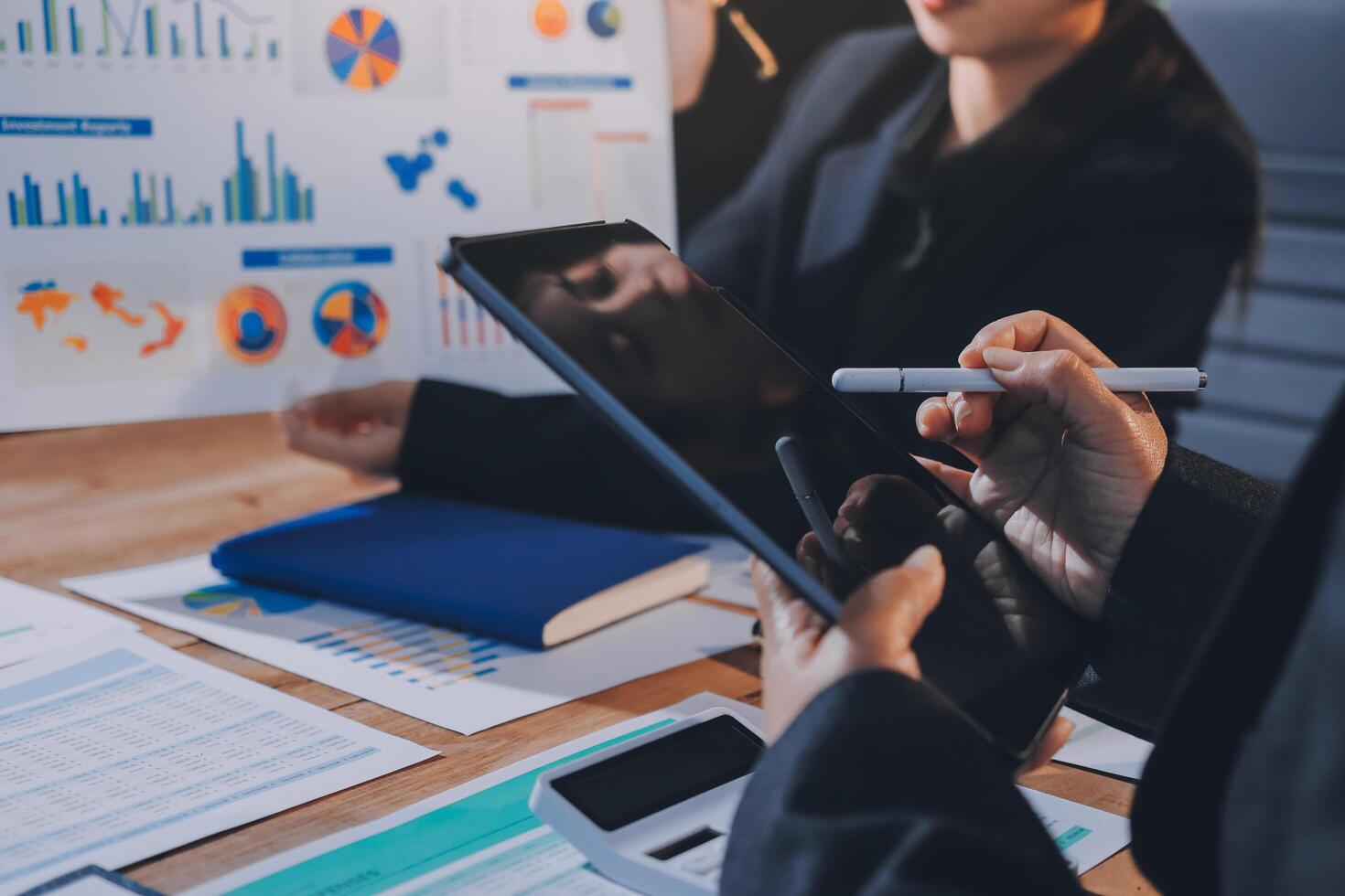 Business people working on a tablet with graphs and charts photo